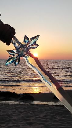 a person holding a glass star on the beach at sunset or sunrise time with water and sand in the foreground