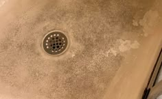 a drain in the middle of a dirty bathroom with dirt on the floor and walls