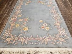 a blue rug with flowers and fringes on the floor