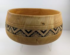 a wooden bowl sitting on top of a white table next to a black and brown pattern