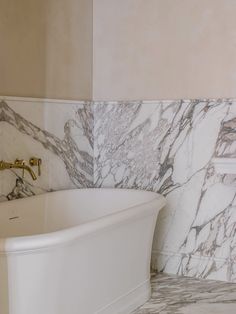 a white bath tub sitting next to a marble tiled wall