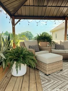 a covered patio with couches and potted plants