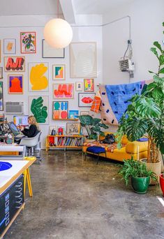 a living room filled with lots of plants and pictures on the wall