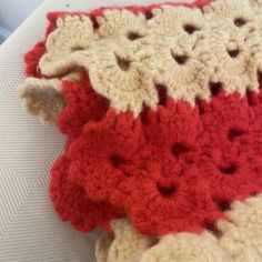 a crocheted red and white blanket on top of a bed next to a pillow