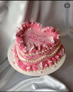 a pink heart shaped cake with butterflies on it's top and the words happy birthday written in white letters