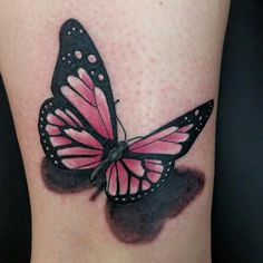 a pink and black butterfly tattoo on the right side of the leg, with dots around it