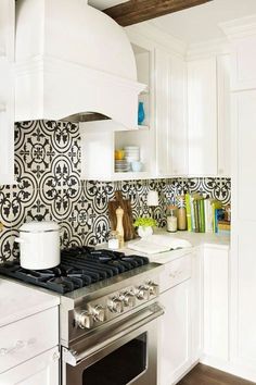 a stove top oven sitting inside of a kitchen next to a wall covered in black and white tiles