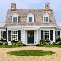 a white house with black shutters and two chimneys on the top of it's roof