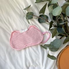 a crocheted pink purse sitting on top of a bed next to a potted plant