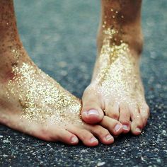 a close up of a person's bare feet covered in sand on the ground