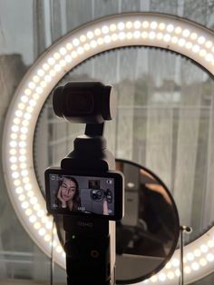 a cell phone sitting on top of a tripod in front of a circular mirror