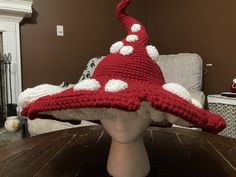 a crocheted red and white hat sitting on top of a wooden table next to a fireplace