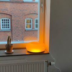 a window sill with an orange light on it in front of a brick building