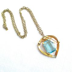 Art Deco style gold metal and turquoise blue rhinestone vintage pendant necklace.  The gold link chain measures 18" long with a fold over snap clasp, working properly.  The heart shape like pendant measures 1 1/4" tall by 1 1/4" wide and features an emerald cut turquoise blue glass stone.  The turquoise stone is prong set with an open and multi faceted back and front side. Feminine and truly charming.  This piece is not hallmarked and is in very good condition. Comes carefully gift boxed for safe and secure delivery.  Combined shipping with all orders.  I ship daily, everyday, except on Sundays, so your parcel may be on its way to you today!  Shipping upgrades, i.e. priority and express are always available.  All of my items listed are VINTAGE items, they are preowned and not in new or unu Necklace Emerald, Vintage Pendant Necklace, Gold Link Chain, Gold Link, Bleu Turquoise, Vintage Pendant, Blue Rhinestones, Style Art, Deco Style