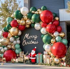 a large christmas wreath with santa clause standing in front of it