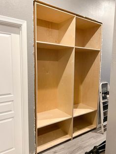 an empty room with some shelves and tools in the foreground, next to a white door