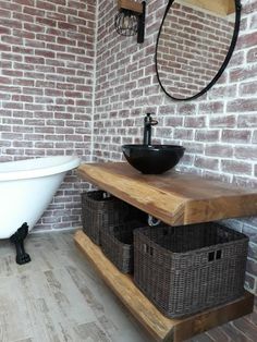 a bath room with a sink and a bath tub next to a brick wall in the background