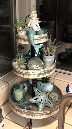 three tiered tray with various sea creatures and plants on it in front of a window