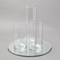 three clear vases sitting on top of a glass plate