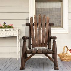 a wooden rocking chair sitting on top of a porch next to a flower pot and basket