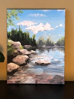 a painting of a river with rocks in the foreground and clouds in the background