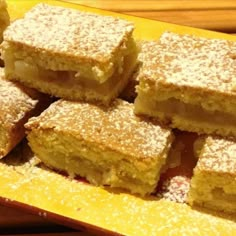 several pieces of cake sitting on top of a yellow platter with powdered sugar