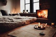 a living room with a fire place in the middle and candles on the floor next to it