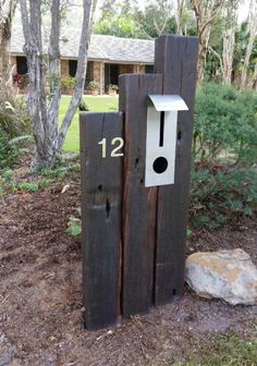 two wooden mailboxes with numbers on them in front of some bushes and trees