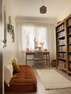 a living room with a couch, bookshelf and desk in the middle of it