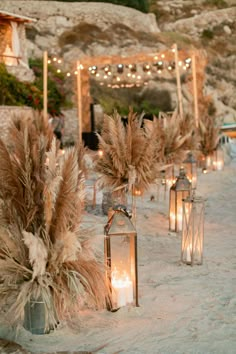 an outdoor wedding setup with candles, flowers and pamodia in vases on the sand