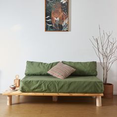 a green couch sitting on top of a hard wood floor next to a potted plant