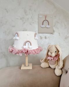 a stuffed bunny sitting on top of a couch next to a small table with a cake