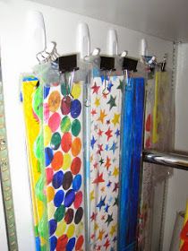 colorful shower curtains are hanging on the wall next to a metal hand towel dispenser