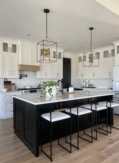 a large kitchen with white cabinets and black island