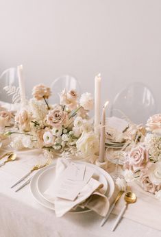 the table is set with white and pink flowers, candles, and place settings for an elegant dinner