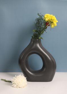 a vase with flowers in it sitting on a table next to a blue wall and a white flower