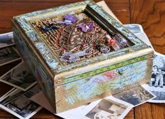 an old box sitting on top of a wooden table filled with pictures and other items