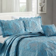 a bed with blue comforters and pillows in a room