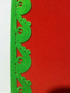 a red and green ribbon with an intricate design on it's side, next to a white background