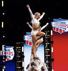 two cheerleaders are performing on top of each other