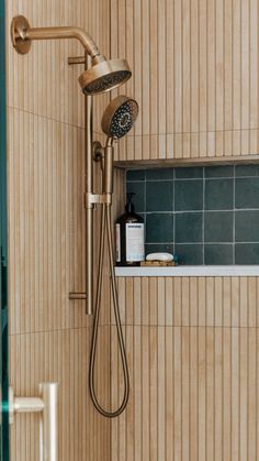 a shower head and hand held shower faucet in a bathroom with wood paneling