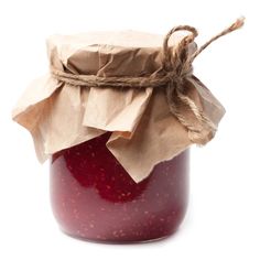 a jar filled with jam sitting on top of a white table next to a brown paper bag