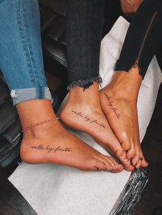 two people sitting on top of a chair with their feet crossed and one has writing on it