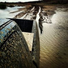 an old boat is sitting in the water at low tide, and it's muddy