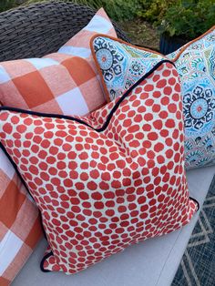 three pillows sitting on top of a white table next to each other in front of plants