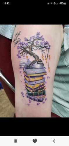 a tattoo with books and a tree on it