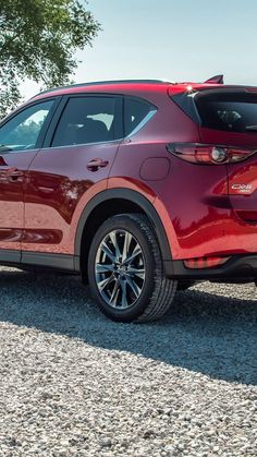 the rear end of a red mazda cx - 5 parked on gravel