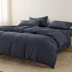 an unmade bed with blue sheets and pillows