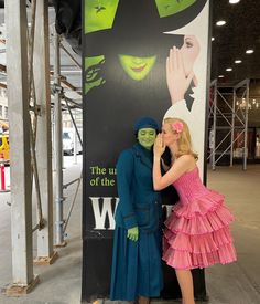 two people dressed in costumes standing next to a sign