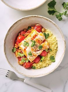 two white bowls filled with food on top of a table next to utensils